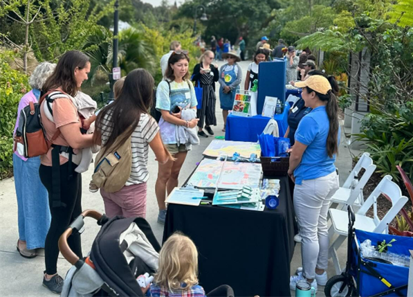 A gathering of attendees viewing an exhibitor table at the Teacher Resource Fair.